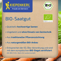 Bio-Saatgutpackung mit Text und Bio-Siegel auf braunem Hintergrund, umgeben von Karotten und grünem Feld.