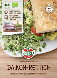 Keimsprossen-Saat auf einem Teller mit Brot, Tomate, Käse und Salat, Verpackung in der Ecke sichtbar.